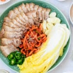 a platter of thinly sliced boiled pork belly served with salted napa cabbge and spicy radish salad