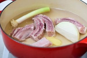 Boiling pork ribs in water with onion, ginger, and green onion for stew