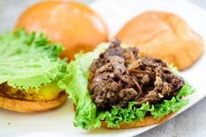 placing bulgogi on a bun with a lettuce leaf