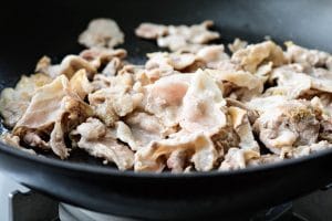 Stir-frying thinly sliced pork belly in a pan
