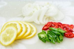 slices of lemon, onion, and chili peppers on a cutting board