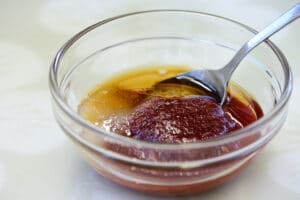 Gochujang, sugar sesame oil in a small glass bowl with a spoon to mix with