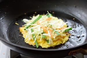 cooking a round veggie omelet in a pan for Korean gilgeori toast