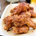 Korean fried chicken with red spicy sauce served on a white plate lined with parchment paper