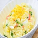 Mayo-based Korean-style potato salad dotted with boiled egg, cucumber, and carrot slices garnished with egg yolk powder