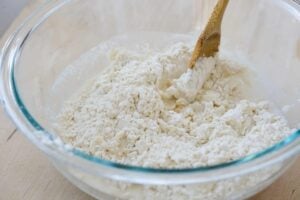 adding water to the flour and mixing with a spoon to make a dough