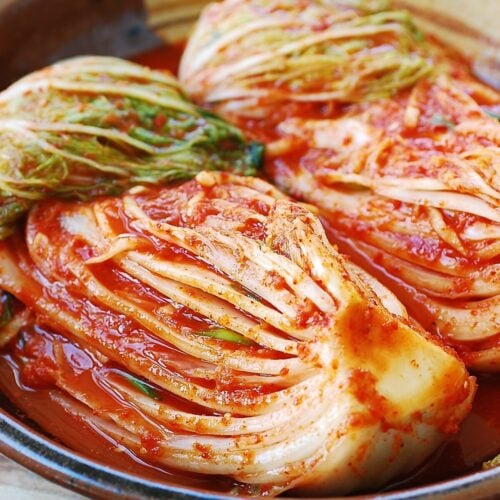 2 quarter-heads of napa cabbage kimchi in a large ceramic bowl