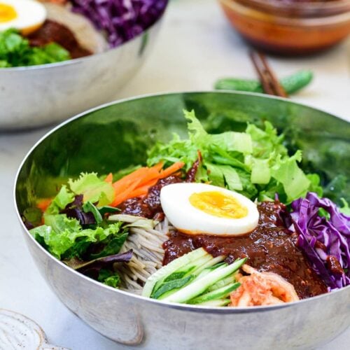 Cold noodles with colorful vegetables and a spicy gochujang sauce with a half boiled egg on top