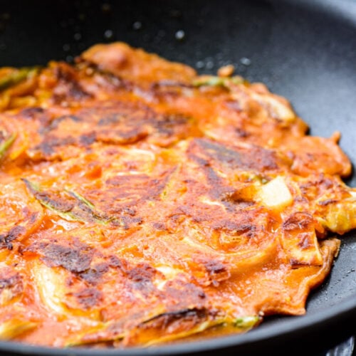 Kimchi pancake being pan fried in a non-stick pan