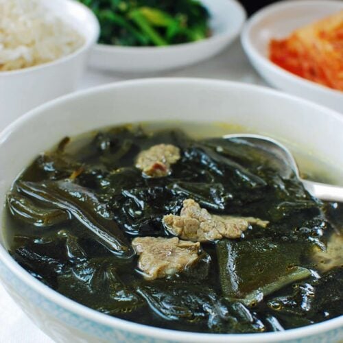 Miyeok guk (seaweed soup) with beef served with a bowl of rice, kimchi and spinach side